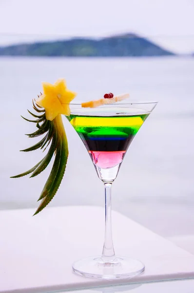 Fresh vibrant colours summer cocktail in a glass on white bar counter natural light. Beach cocktail with pineapple decoration