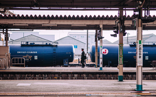 DEC 4, 2018 Koriyama, JAPAN - Нефтяной поезд, нефтеналивной поезд с офицером кондукторной станции, идущим по платформе на станции Корияма
