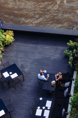 8 Mayıs 2013 Bangkok, THAILAND - Bangkok açık hava restoranı, nehir manzaralı yemek masaları. Turistler nehir kenarında içiyor, doğal yaz güneşi.