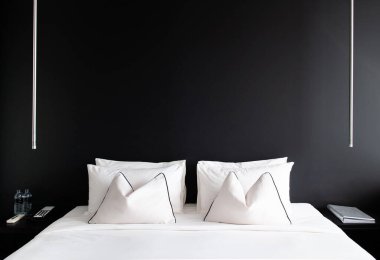 MAY 8,2013 Bangkok, THAILAND - Bedroom with black concrete wall white bed, white pillows and simple design side table, lamp. Modern urban interior with black and white colours tone clipart
