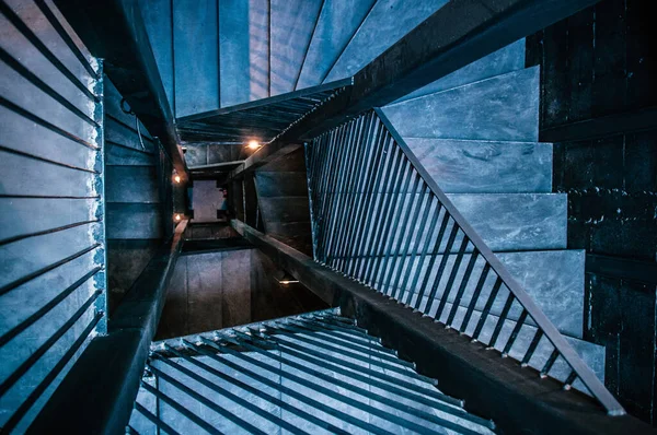 Industrial loft spiral staircase with concrete floor, black metal handrail, cold tone image, shot from top