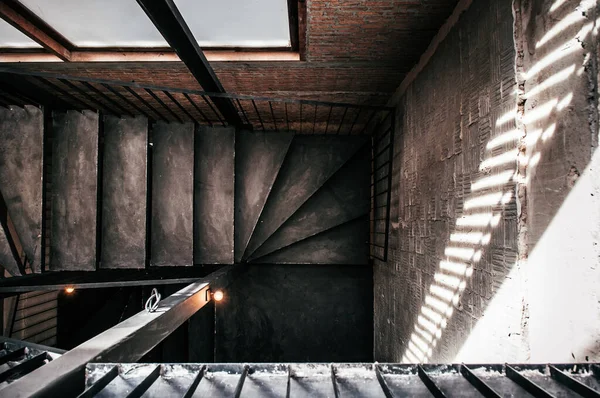 Industrial loft old staircase with concrete floor, black metal handrail and brick wall, dark tone image, shot from top