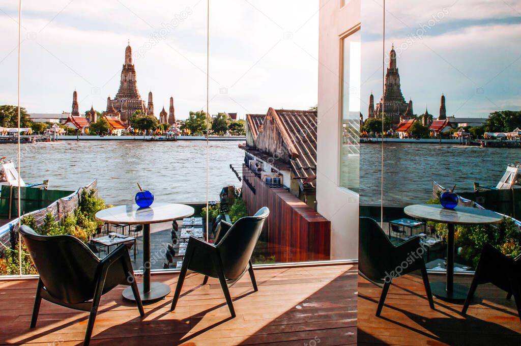 MAY 8,2013 Bangkok, THAILAND - Bangkok fine dining restaurant with marble dinner tables, stylish design armchairs river view at Wat Arun temple, natural evening sunlight and reflection on glass wall