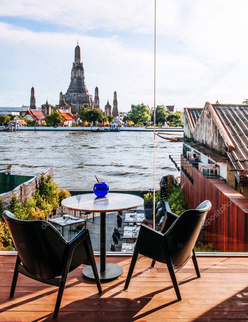 MAY 8,2013 Bangkok, THAILAND - Bangkok fine dining restaurant with marble dinner tables, stylish design armchairs river view at Wat Arun temple, natural evening sunlight
