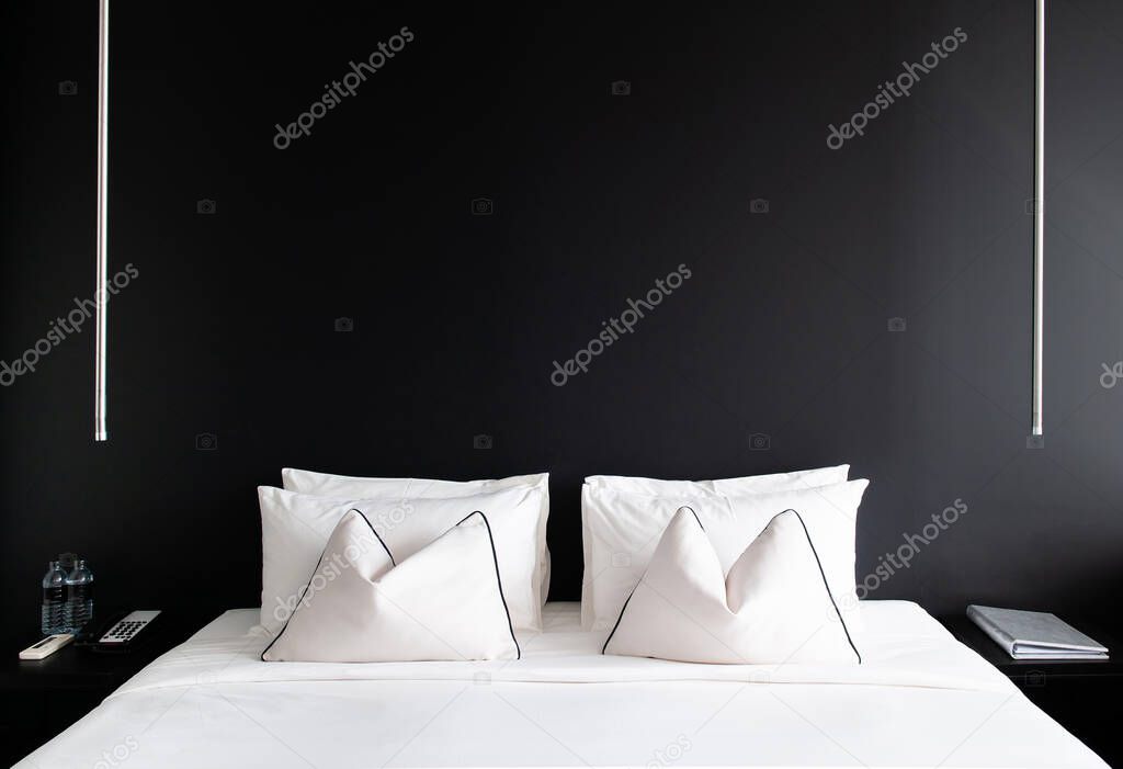 MAY 8,2013 Bangkok, THAILAND - Bedroom with black concrete wall white bed, white pillows and simple design side table, lamp. Modern urban interior with black and white colours tone