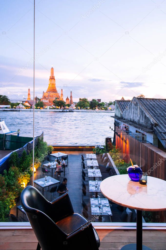 MAY 8,2013 Bangkok, THAILAND - Bangkok fine dining restaurant with marble dinner tables, stylish design armchairs river view at Wat Arun temple, natural evening sunlight