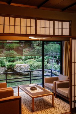 25 Mayıs 2013 Gifu, JAPAN - Sürgülü kapıları, ahşap masası ve eski tasarım koltukları olan eski bir Japon otel salonu. Ilık ışık ve bahçe manzaralı atmosfer