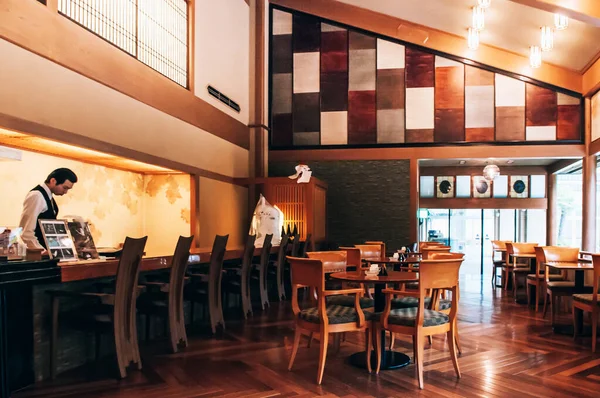 2013年5月25日岐阜県岐阜市 ヴィンテージ木のテーブルとレトロなデザインの椅子 古い木の床を持つ日本の伝統的なダイニングルーム カウンターの後ろに働く天井ランプやレストランのスタッフから暖かい光 — ストック写真