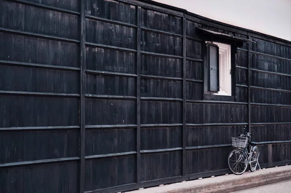 Japanese vintage white bicycle with painted black pine wood wall of old house. Hida Furukawa, Gifu - Japan