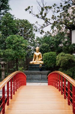 27 Haziran 2014 - Kawasaki, Japonya: Japon bahçesinin güzel mimari manzarası, kırmızı köprü ve Kawasaki Daishi Tapınağının altın Buda heykeli