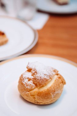 Vanilyalı kremalı enfes Choux puf ve üstüne krema. Kahve molası, sade beyaz tabakta..