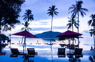 23 Mayıs 2010 Phuket, Tayland - Sonsuz kenar havuz Yazın mavi gökyüzü altında Plaj şemsiyeleri ve okyanus manzaralı Phuket 'teki tropikal ada tatil köyünde.