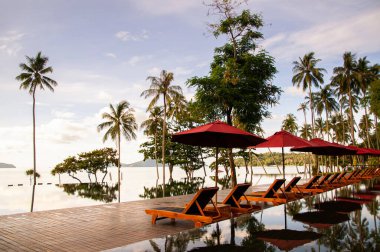 23 Mayıs 2010 Phuket, Tayland - Sonsuz kenar havuz yazın mavi gökyüzü altında plaj şemsiyeleri ve okyanus manzaralı Phuket 'teki tropik ada tatil beldesinde.