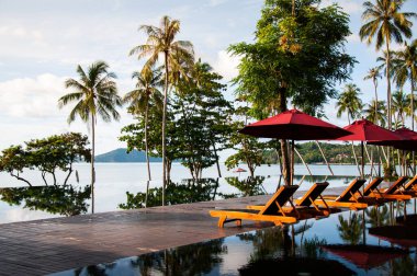 23 Mayıs 2010 Phuket, Tayland - Sonsuz kenar havuz yazın mavi gökyüzü altında plaj şemsiyeleri ve okyanus manzaralı Phuket 'teki tropik ada tatil beldesinde.