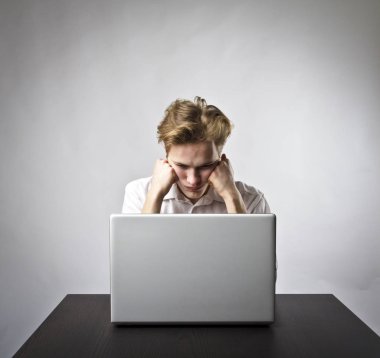 Net göz atmak için bir dizüstü bilgisayar kullanan genç adam.