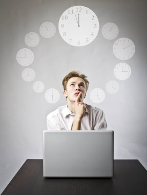 Young man using a laptop to browse the net. Man in white and clock. Three Minutes to Twelve. Time is passing. Workday concept. clipart