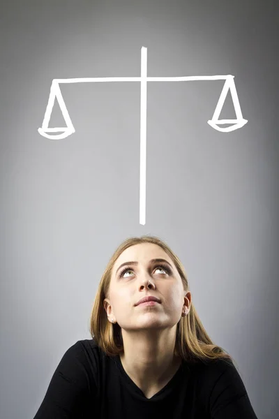 Jonge vrouw in het zwart is vol van twijfels en aarzelingen. Schalen. — Stockfoto