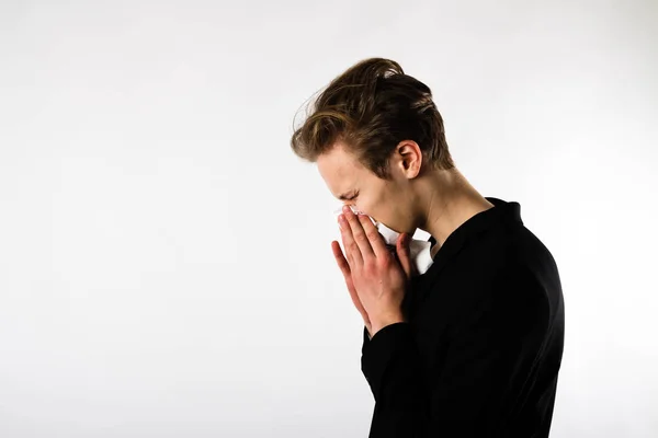 Young man in black is sneezing — Stock Photo, Image
