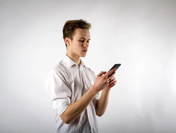 Ung man i vit med smartphone — Stockfoto