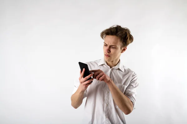 Jonge man in wit met smartphone — Stockfoto