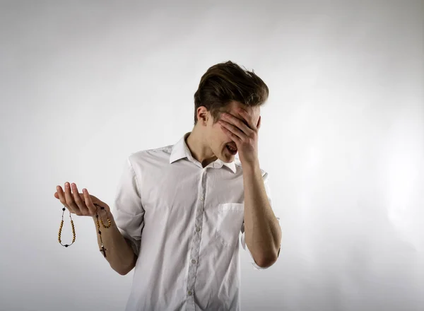 Junger Mann betet mit Rosenkranzperlen. — Stockfoto