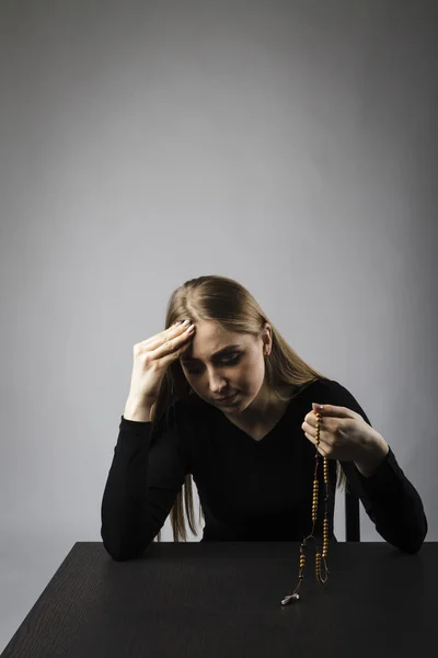 Junge Frau betet mit Rosenkranzperlen. — Stockfoto