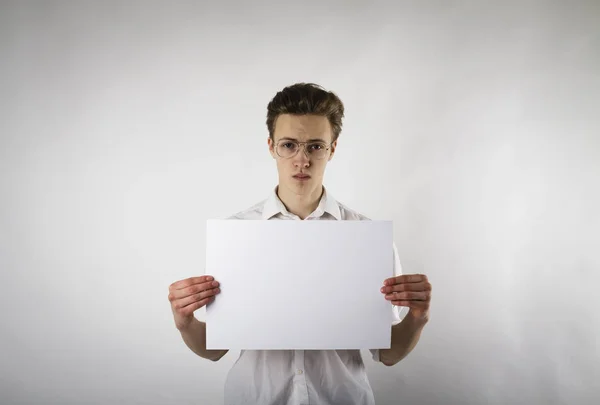 Молодой человек держит в руках белую бумагу. Серьезный человек с Гла — стоковое фото