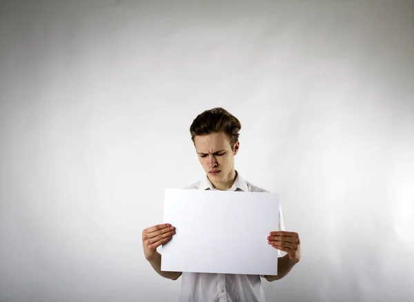 Young man holding white paper in his hands. Unhappy man. — 图库照片