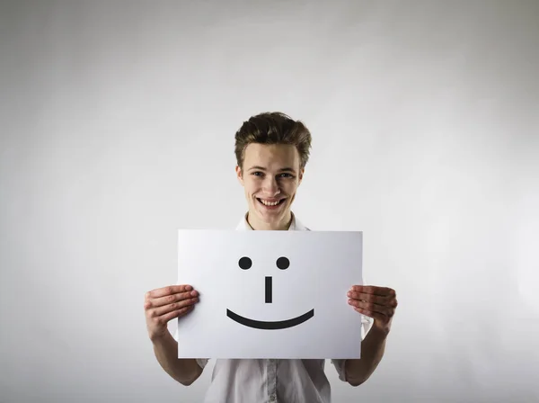 Le jeune homme tient le papier blanc avec le sourire. Un homme heureux . — Photo