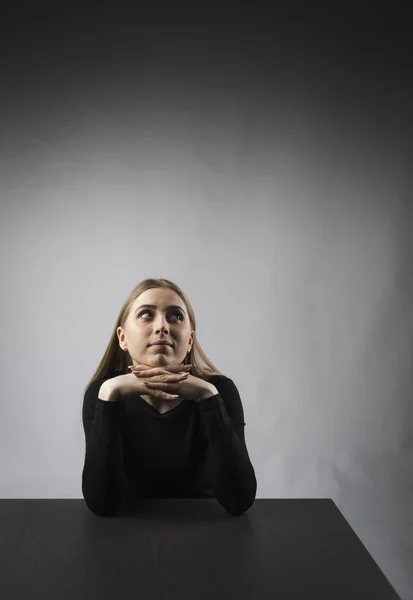 Jonge vrouw in zwart zit aan de tafel. — Stockfoto