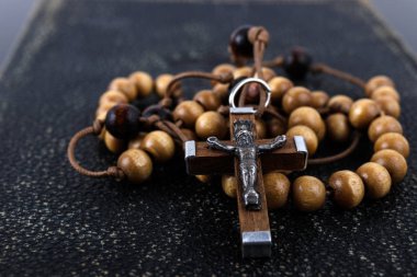 Rosary beads and prayer book on dark background. clipart