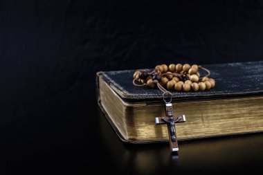 Rosary beads and prayer book on dark background. clipart