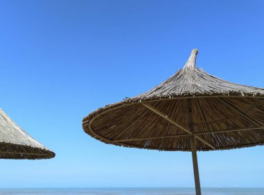 Mavi gökyüzüne karşı saman şemsiyeler. Şemsiye. 