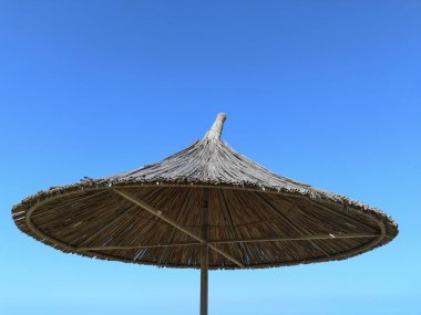 Mavi gökyüzüne karşı saman şemsiyeler. Şemsiye. 