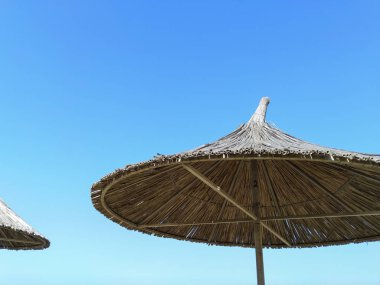 Mavi gökyüzüne karşı saman şemsiyeler. Şemsiye. 
