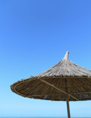 Mavi gökyüzüne karşı saman şemsiyeler. Şemsiye. 