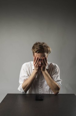 Beyazlar içindeki yorgun genç adam. Hayal kırıklığı, baş ağrısı ve yorgunluk konsepti. Kendimi kötü hissediyorum. Akıllı telefonlu bir iş adamı..