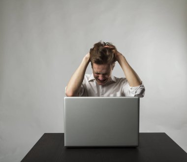 Laptoplu sinirli genç adam. Beyazlı adam baş ağrısından muzdarip. İfadeler, duygular ve ruh halleri.