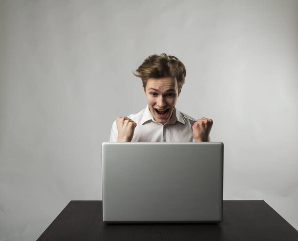 Молодой счастливый человек с ноутбуком. Концепция успеха. Молодой человек использует ноутбук для просмотра сети.