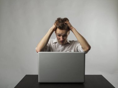 Laptoplu sinirli genç adam. Beyazlı adam baş ağrısından muzdarip. İfadeler, duygular ve ruh halleri.