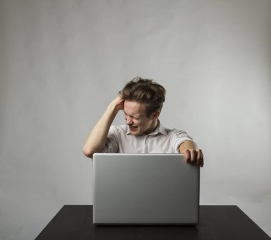 Laptoplu sinirli genç adam. İfadeler, duygular ve ruh halleri. Evde öğreniyorum..