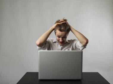 Laptoplu sinirli genç adam. İfadeler, duygular ve ruh halleri. Evde öğreniyorum..