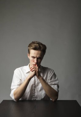 Masada oturan beyazlı genç adam. Ciddi adam..