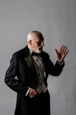 Paltolu yaşlı adam. Sakallı yaşlı bir adamın portresi. Gri arka planda frak giymiş kıdemli bir adam..