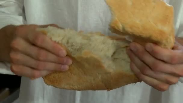 Las manos de los hombres rompen una barra de pan fresco — Vídeo de stock