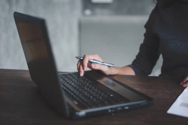 Onun iş istasyonu dizüstü bilgisayarda çalışan genç iş kadını.