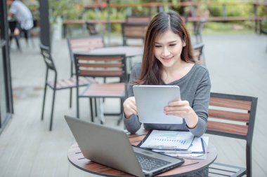 Seçici odak onun resepsiyon işkadını ofiste oturan ve dizüstü bilgisayar kullanan dizüstü kadın üzerinde çalışma, otururken dizüstü bilgisayar kullanan çalışma alanı'nı kadın üzerinde oturan genç çekici Asya iş kadın.