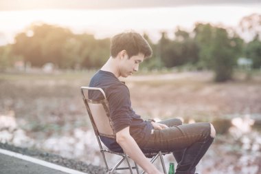 yakışıklı delikanlı taşlı sahilde bira içme portresi