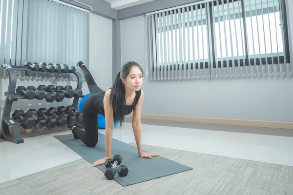 spor salonunda yerde kadının yapması germe egzersizleri