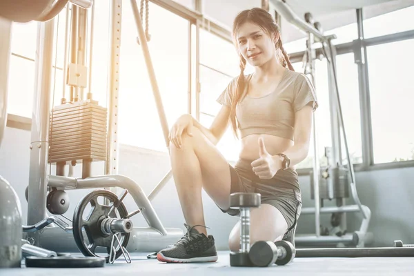 Genç Asyalı güzel kadın dumbbell pazı insanlar arka plan, vücut geliştirmeci, sağlıklı yaşam, egzersiz fitness, egzersiz ve spor eğitim kavramı, yumuşak odak fitness salonunda, ile yapıyor